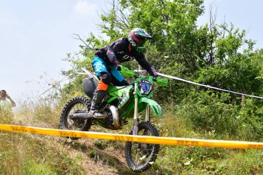 25 Haziran 2023, Veles, Makedonya. Enduro ekstrem moto yarışında sürücüler zorlu bir arazide lastiklerin üzerinden atlayarak ve dağ yollarında 40 kilometrelik bir sürüş yaparak yarıştılar..