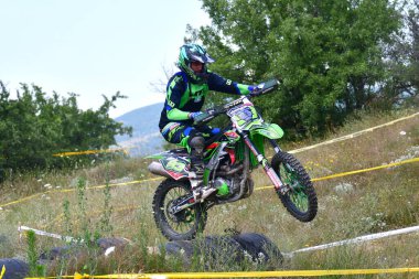 25 Haziran 2023, Veles, Makedonya. Enduro ekstrem moto yarışında sürücüler zorlu bir arazide lastiklerin üzerinden atlayarak ve dağ yollarında 40 kilometrelik bir sürüş yaparak yarıştılar..