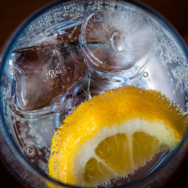 Soğuk içecek bir bardak köpüklü su, buz ve limon ile yenileme.