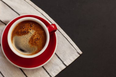 Coffee concept, red cup, hot coffee on black background with space for text, top view