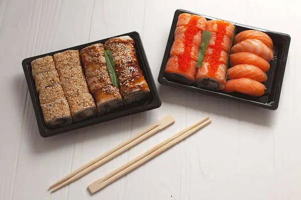 Japon yemeği. Beyaz ahşap arka planda soya soslu somon suşisi nigiri. Paket yemek.