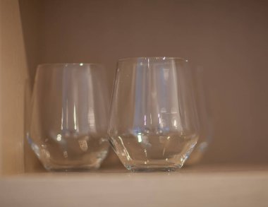 Tahta raflarda uzun bardakları temizle, sığ alan derinliği, yakın cama odaklan diğerlerini bulanık bırak.