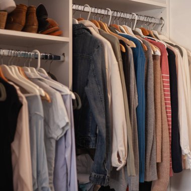 Beyaz dolap kapanıyor, elbiseler askılarda ve ayakkabılarda asılı, kare biçiminde.