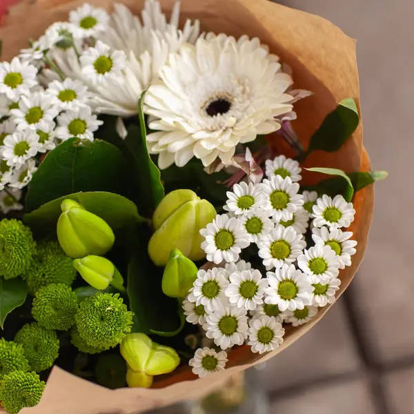 Sarılı yeşil ve beyaz çiçekler, el işi kağıdına sarılı buket..