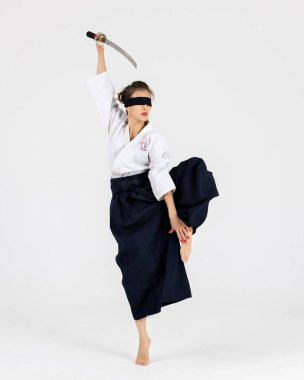 Geleneksel samuray hakama kimonosuyla Aikido üstadı kadın. Kılıçlı siyah kuşak, beyaz arka planda katana. Sağlıklı yaşam tarzı ve spor anlayışı.