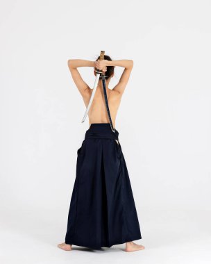 Geleneksel samuray hakama kimonosuyla Aikido üstadı kadın. Kılıçlı siyah kuşak, beyaz arka planda katana. Sağlıklı yaşam tarzı ve spor anlayışı.