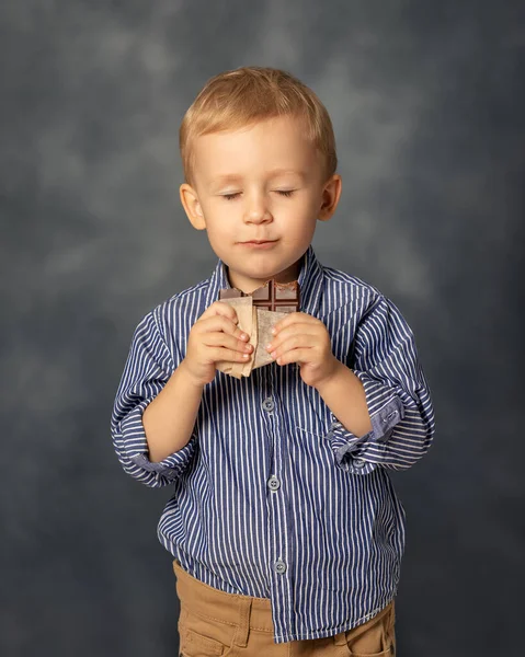 Porträt Eines Kleinen Jungen Der Schokolade Auf Grauem Hintergrund Isst — Stockfoto