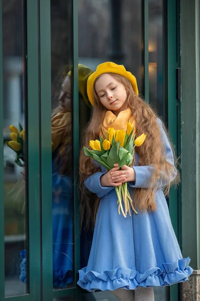 春天里 一个快乐的姑娘带着一束黄色的郁金香散步的画像 国际妇女日的花朵 春天和童年的概念 免版税图库照片