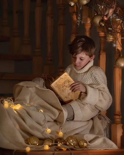 クリスマスの階段の近くに素晴らしい箱と贈り物を持って座っている少年 新しい年 幸せと妖精の物語 ロイヤリティフリーのストック画像