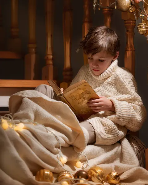 圣诞节的时候 男孩带着一个神奇的盒子和礼物坐在楼梯旁边 新年快乐童话故事 图库照片