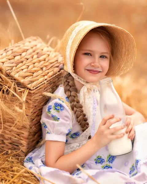 日没の小麦畑で幸せな女の子の肖像画 子供は ライ麦の耳の背景に対してミルクを持つガラス瓶を保持しています 自然のピクニック ストック画像