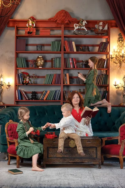 Happy grandma and grandchildren reading book together and having fun at home