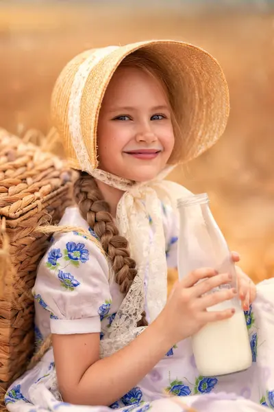 日没の小麦畑で幸せな女の子の肖像画 子供は ライ麦の耳の背景に対してミルクを持つガラス瓶を保持しています 自然のピクニック ストックフォト