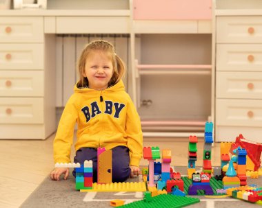 Renkli plastik bloklarla oynayan küçük bir kız. Lego Duplo. Anaokulu eğlencesinde inşaat oyuncağı yapan kadın çocuk. Montessori ve erken gelişim