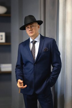 Sigara içerken camında sigara olan takım elbiseli yakışıklı bir iş adamı.