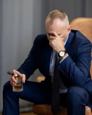 Takım elbiseli iş adamı viski içer. Adam elinde brendi bardağı tutuyor. Tatma ve degukasyon konsepti. Sommelier 'in pahalı bir içeceği var..