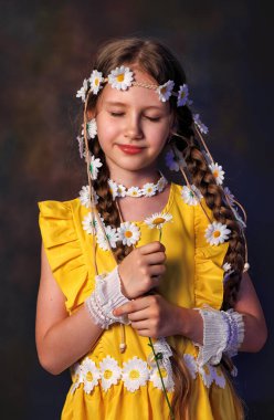 Kafasında papatya çelengi ve gri arka planda poz veren güzel beyaz bir kızın yakın portresi. Güzel kıvırcık saçlar.