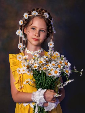Kafasında papatya çelengi ve gri arka planda poz veren güzel beyaz bir kızın yakın portresi. Güzel kıvırcık saçlar.