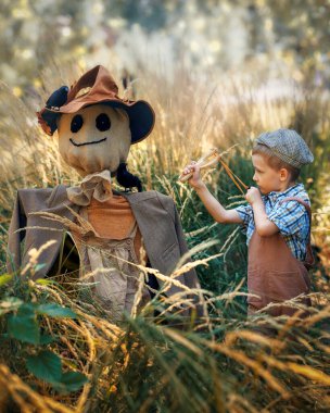 Bahçesinde karga kuşları ve mutlu çocuk olan korkuluk sonbahar hasadı, Şükran Günü sebzesi, Cadılar Bayramı