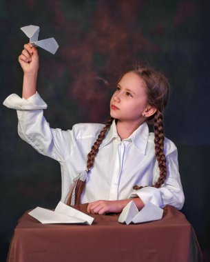 Siyah arka planda genç bir kızın portresi. Elinde kağıt uçak oyuncağı olan bir çocuk. Güzel bir gencin yüzü. Sanatsal fotoğrafçılık.