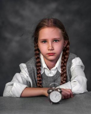 Siyah arka planda çalar saati olan genç bir kızın portresi. Yavrum. Genç ve güzel bir kızın yüzü. Sanatsal fotoğrafçılık.