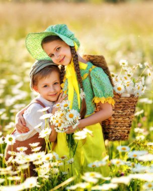 Yaz cazibesi: Papatyalı yeşil şapkalı çocuk. Çiçek tarlasında mutlu kardeşler. Çocuklar erkek ve kız kardeş