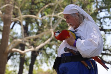 4-15-2023: Visalia, California: Dönem kostümlü insanlar Rönesans Fuarında papağan gösterisi yapıyorlar