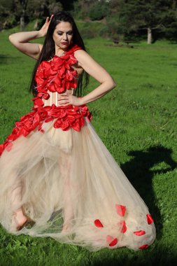 Parkta dalgalı kırmızı elbiseli güzel beyaz bir kadının fotoğrafı.
