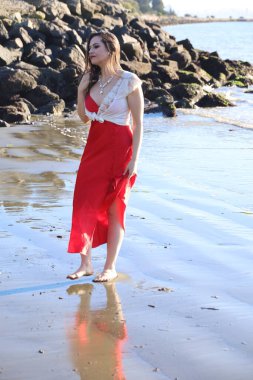 Suya yakın bir plajda duran güzel beyaz bir kadının fotoğrafı.