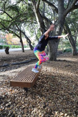 Olgun Vietnamlı bir kadının parkta bir bankta zıplamasının fotoğrafı.