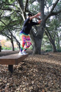 Olgun Vietnamlı bir kadının parkta bir bankta zıplamasının fotoğrafı.
