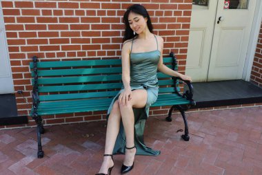 Güzel bir Asyalı Çinli kadın modelin fotoğrafı, bankta yatıyor.