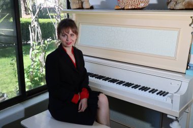 Kütüphanede, bir piyanonun önünde güzel bir Rus Modelinin fotoğrafı.