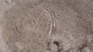 Deniz kıyısındaki temiz kumda su damlaları birikintiye düşer. Çemberler ve sıçramalar deniz suyunda oluşur. Suya sıçra, ferahla. Yaz mevsimi deniz kıyısında dinlenme ve eğlence