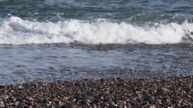 Çakıl taşı plajı ve temiz deniz köpüğüyle deniz dalgaları. Akdeniz kıyısının deniz manzarası. Barselona İspanya 'nın ıslak çakıl taşlı sahilinde kıyı dalgaları. Sant Miquel plajında deniz manzaralı kimse yok. Yaz tatili
