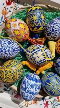 Paskalya yumurtalarının canlı çeşitleri, karmaşık halk örnekleri sergileyerek geleneksel Ukrayna pisazan tekniklerini sergiliyor. Paskalya kutlaması için dekoratif bir sepete güzelce yerleştirilmiş..