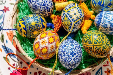 Parlak renkli Paskalya yumurtaları bir Paskalya sepetinde sanatsal olarak düzenlenmiştir. Geleneksel Ukrayna Pysanky 'si ayrıntılı halk figürleriyle süslenmiştir..