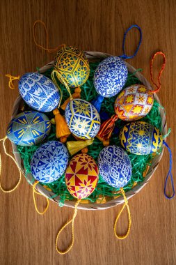Geleneksel Ukrayna pisansi desenleriyle süslenmiş canlı Paskalya yumurtaları zarif bir sepetin içinde duruyor. Her yumurta sergisi, festival sezonunda kültürel sanatın kutlanacağı halk tasarımlarını ayrıntılı olarak sunar..