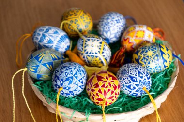 Güzel dekore edilmiş Paskalya yumurtalarıyla dolu bir sepette her biri canlı renklerde karmaşık halk desenleri sergiliyor..