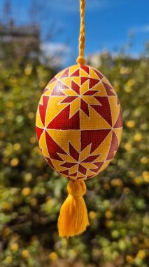 Pysanka geleneksel Paskalya temalarını sembolize ederek kırmızı ve sarı desenler sergiliyor..