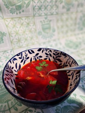 Geleneksel bir Ukrayna pancar çorbası olan Borscht, canlı kırmızı bir renk ve lezzet için taze bitki parçacıklarıyla dekoratif bir kasede güzelce sunulmaktadır. Sıcak bir yemek için mükemmel..