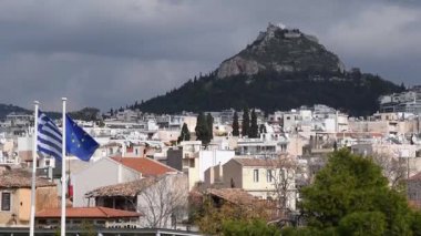 Atina 'daki Lycabettus Dağı' nın nefes kesici manzarasını görün. Çevresindeki şehir manzarası, Avrupa Birliği ve Yunanistan 'ın bayraklarını sallayarak Yunan manzarasının güzelliğini gözler önüne seriyor.