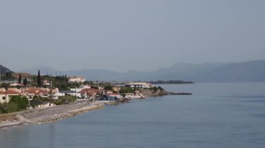 Mavra Litharia Yunanistan 'ı keşfetmek, sakin sularıyla güzel kıyı manzarası sergilemek, parlak gökyüzü altındaki büyüleyici köyleri ve dağları yansıtmak. Kamera terasotta kiremitlerine hareket ediyor.