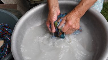 Yaşlı eller eski havuzda çamaşır yıkarlar. Çamaşır makinesini kullanmak yerine çamaşır yıkamanın modası geçmiş bir yolu. Kırışık eller sabun suyunda el yıkama tekstili. Yaşlılar emeklilikten sonra yoksulluk içinde yaşıyorlar.