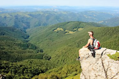 Bir dağcı yüksek bir dağ zirvesinden manzaranın tadını çıkarır.