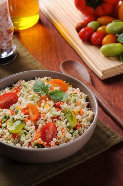 Domatesler, biberler ve bir bardak zeytinyağıyla çevrili kırsal bir kasede sebzeli kuskus. Fas kuskusu. Seçici odak.