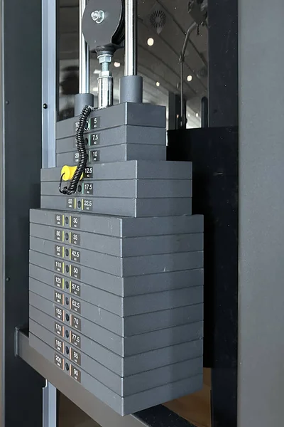Stacked grey metal or iron heavy plates for sports, exercise, weight machine with kilogram and pound numbers in the gym with blurred grey background.