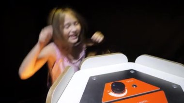 Liseli kız perküsyon orkestrasının temposunu ayarlıyor. Çocuk zıplıyor ve siyah arka planda yanıp sönen ampulün ritmine alkışlıyor