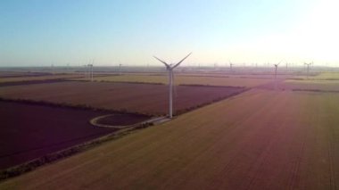 Rüzgar jeneratörleri açık mavi gökyüzüne karşı temiz enerji sağlıyor. Modern türbinler kırsal kesimde elektrik üretiyor