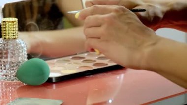 Genç kadın sanatçının manikürlü elleri, müşteriyle yüz tanıma stüdyosunda buluşmadan önce iş yerini hazırlar. Profesyonel kadın siyah göz farı paletini yakına açıyor.